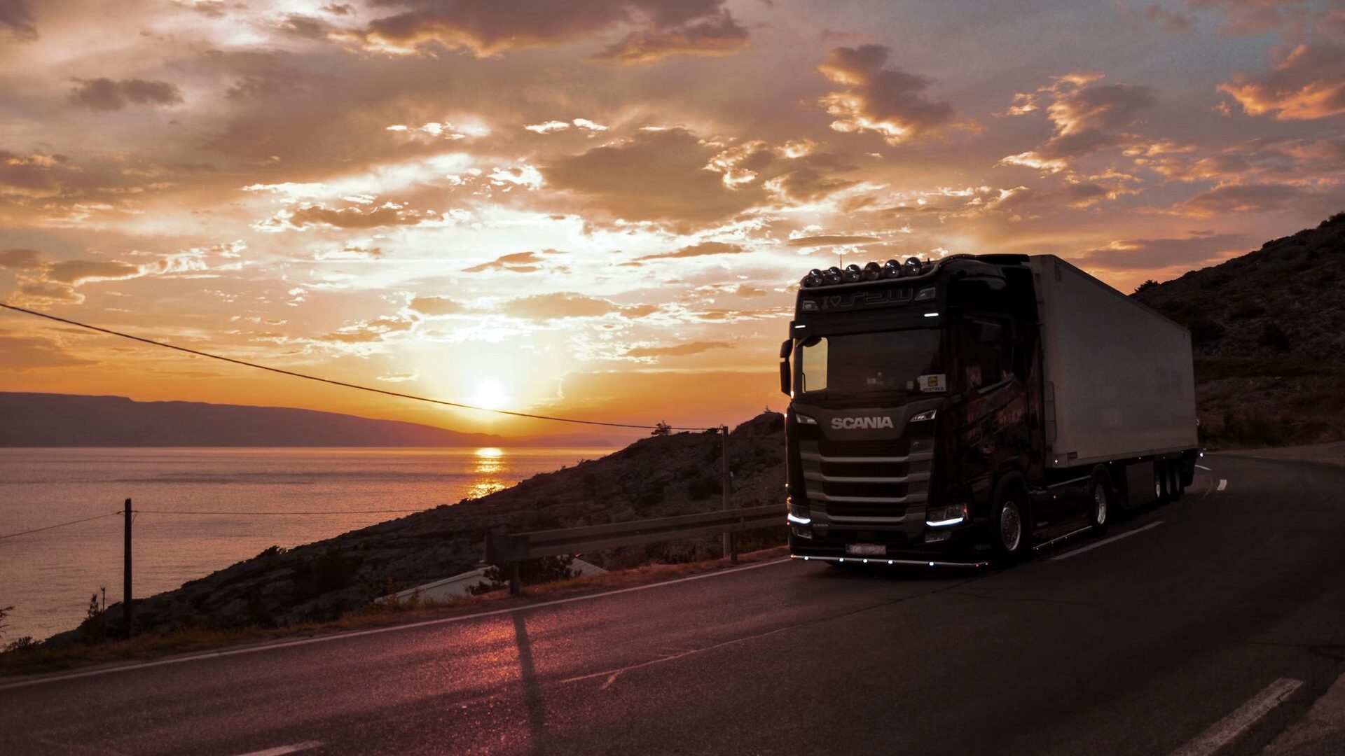 A truck driving into the sunset on an open road